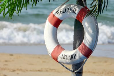 Photo of beach with lifebuoy that says "Welcome Aboard" Photo by Nick Fewings on Unsplash
